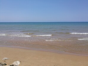 Ein Strand mit blauem Himmel und ruhigem Wasser.