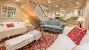 A spacious living room with a high ceiling, a staircase, and a kitchen in the background. - Rural retreat in Hertfordshire near the idyllic medieval village of Ashwell   (Ashwell)