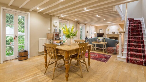A spacious living area with a wooden dining table, a sofa, and a fireplace. - Rural retreat in Hertfordshire near the idyllic medieval village of Ashwell   (Ashwell)