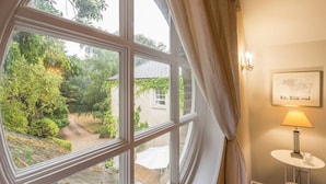 A room with a large window, a small table with a lamp, and a framed map on the wall. - Rural retreat in Hertfordshire near the idyllic medieval village of Ashwell   (Ashwell)