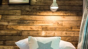Ein Bett mit einem sternförmigen Kissen, eine gerahmte Architekturzeichnung an der Wand und eine Pendelleuchte.