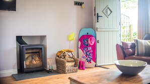 Ein gemütliches Wohnzimmer mit Kamin, einem Surfbrett und einer Tür nach draußen.