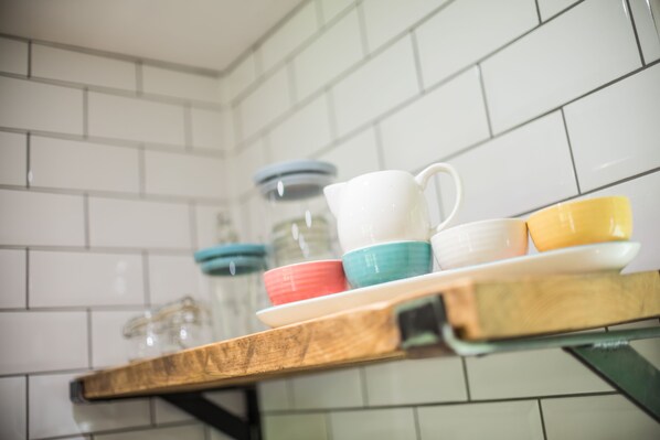 A kitchen shelf with colorful ceramic cups and a white pitcher. - Kingfisher is Laid back luxury in 9-acres of countryside right near the beach (Kilkhampton)