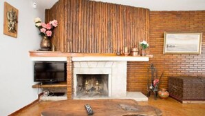 Ein Wohnzimmer mit Kamin, Fernseher und Couchtisch aus Holz.