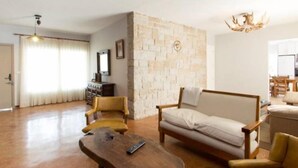 Ein Wohnzimmer mit einer Wand aus Stein, einem Sofa, einem Holztisch und einer Kronleuchter.