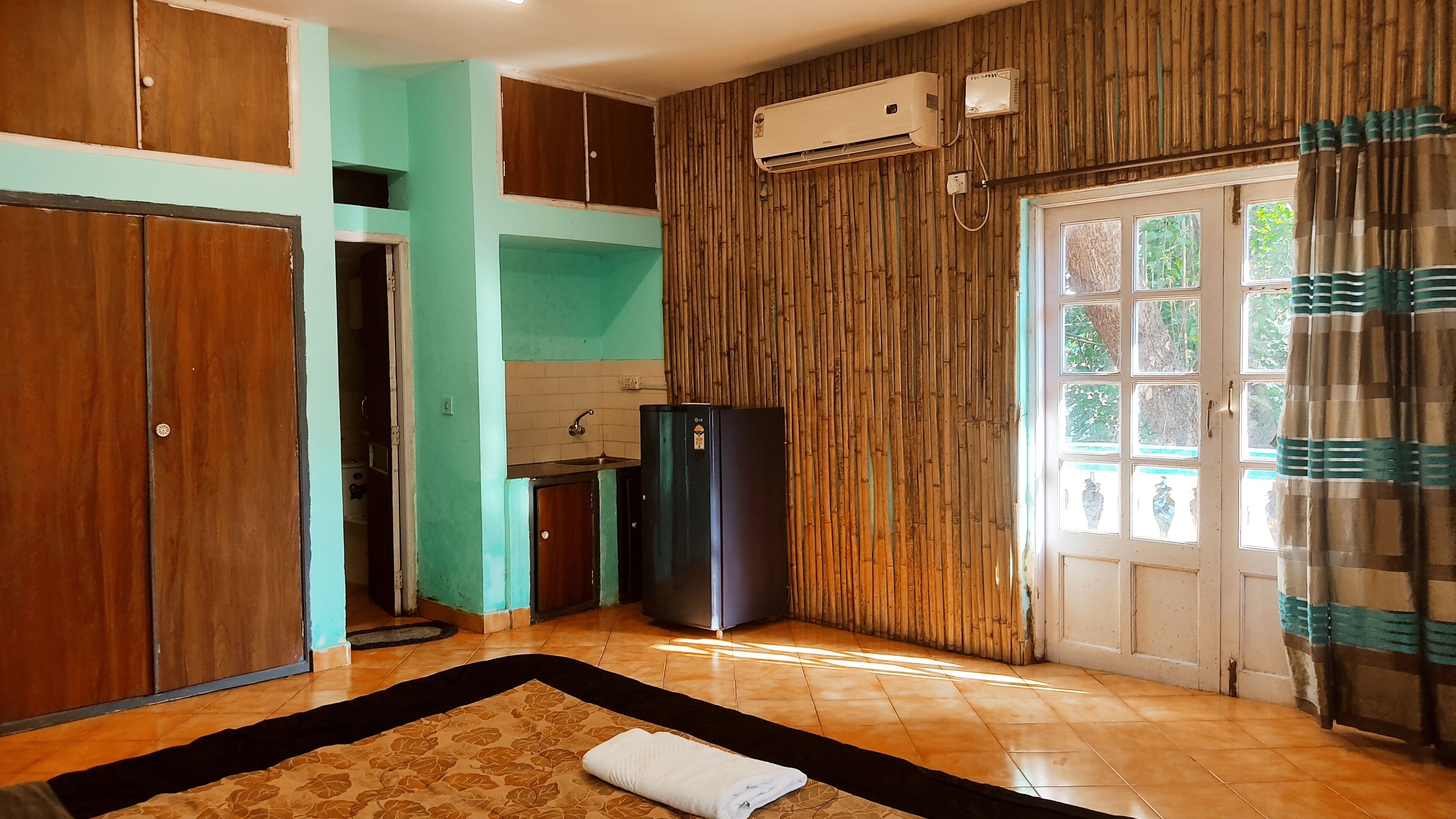 A kitchen with a refrigerator, a sink, and a window with a view of greenery.