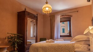 Ein Hotelzimmer mit Bett, einem großen Spiegel, einer Zimmerpflanze und einem Fenster mit Blick auf Gebäude.