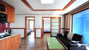 A compact living space with a kitchenette, a sofa, a dining table, and a large window offering a view. - Dream & Green Pension (Seogwipo)