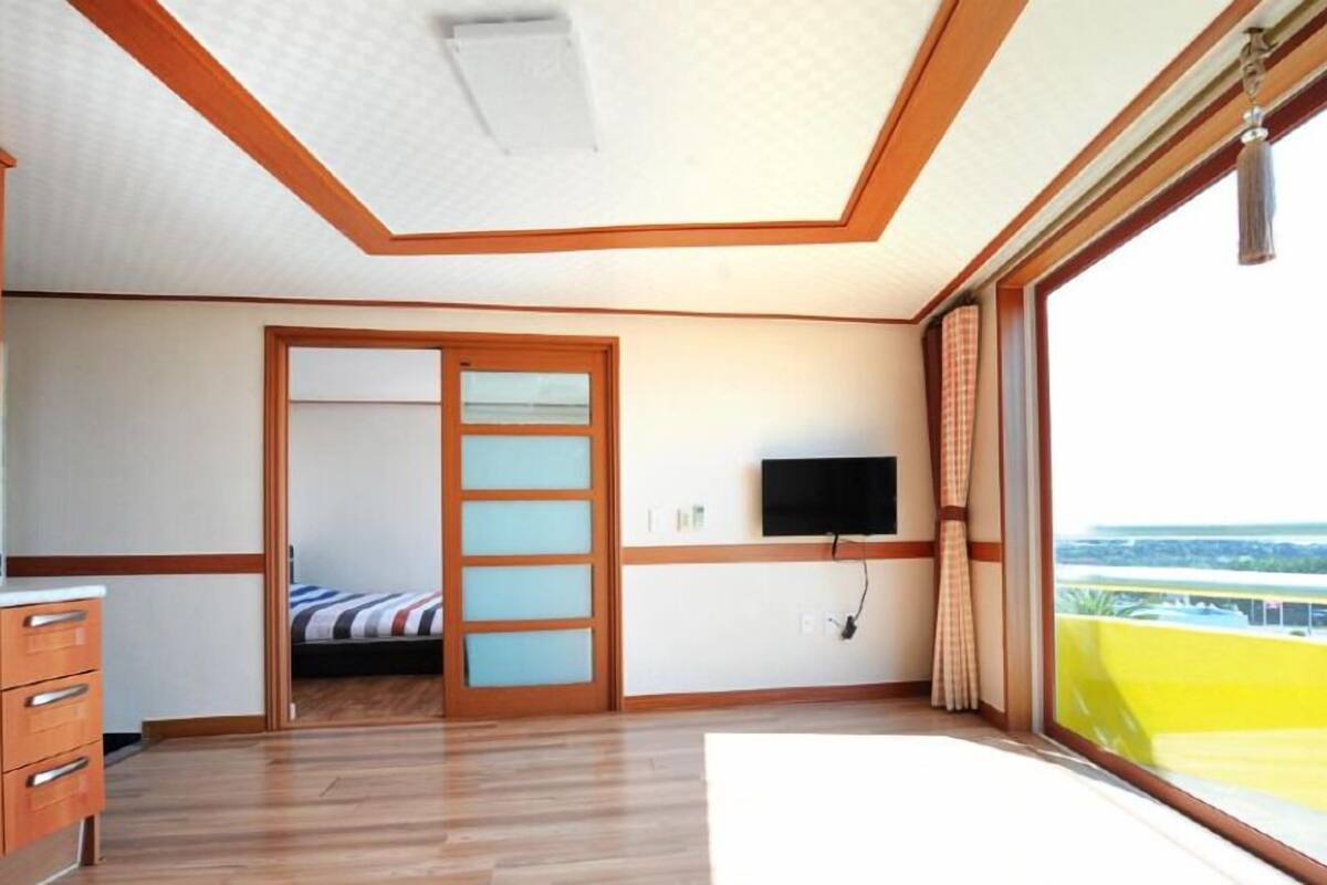 A bedroom with a bed, a TV, a wardrobe, and a window with a view.