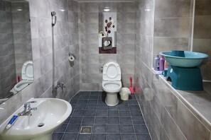 A bathroom with two toilets, a sink, a shower, and a bathtub.