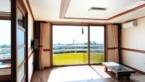A room with a large sliding glass door leading to a balcony, a small table, and a bench. - Dream & Green Pension (Seogwipo)