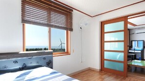 A bedroom with a large window, a view of wind turbines, a bathtub, and a sliding glass door leading to a bathroom. - Dream & Green Pension (Seogwipo)