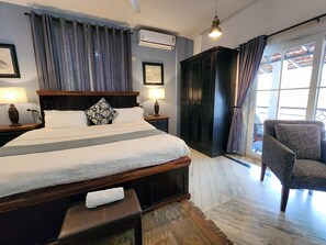 Une chambre d’hôtel avec un grand lit, une armoire, une chaise et une fenêtre avec des rideaux.