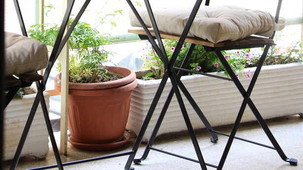 A patio area with a table, a bench, potted plants, and a view of the surrounding buildings. - The easiest way to enjoy Rome (Roma)