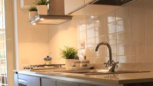 A modern kitchen with a stainless steel sink, dark wooden cabinets, and a green rug. - The easiest way to enjoy Rome (Roma)