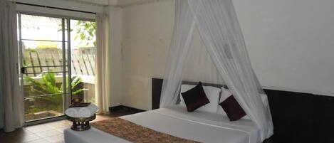 A bedroom with a bed, a canopy, a nightstand, and a view of the outdoors.
