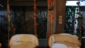 Two wicker swing chairs with cushions, a decorative plant wall, and a 'Free WiFi' sign. - Baan Pim (Chiang Mai)