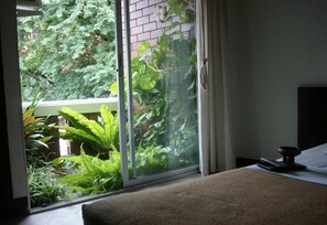 A room with a sliding glass door leading to a balcony with lush greenery. - Baan Pim (Chiang Mai)