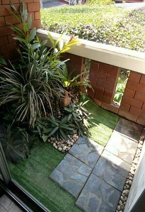 A small, enclosed outdoor area with a brick wall, a stone pathway, and various potted plants. - Baan Pim (Chiang Mai)