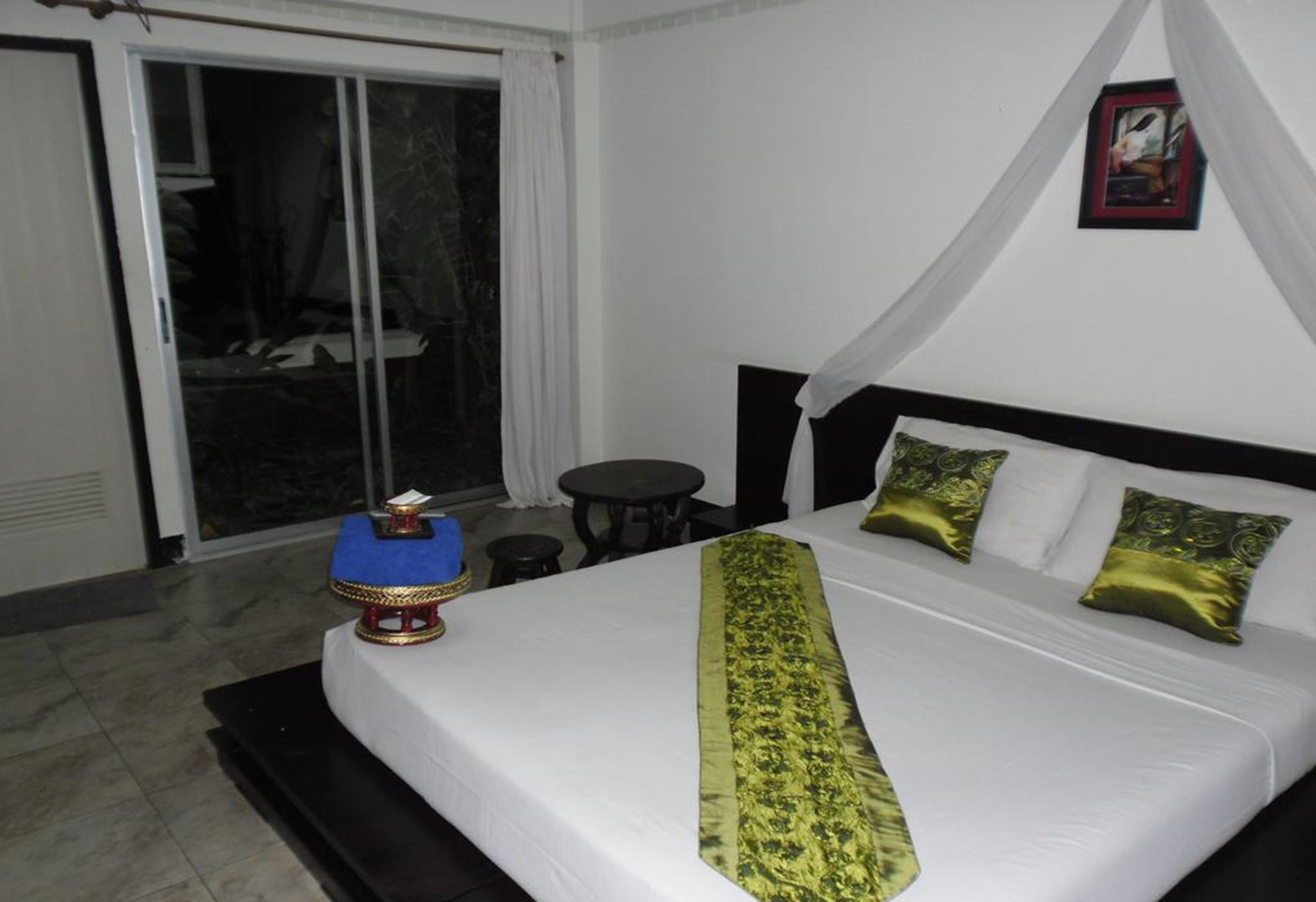 Une chambre d’hôtel avec un lit, une petite table, une chaise et une vue sur l’extérieur grâce à une porte coulissante.