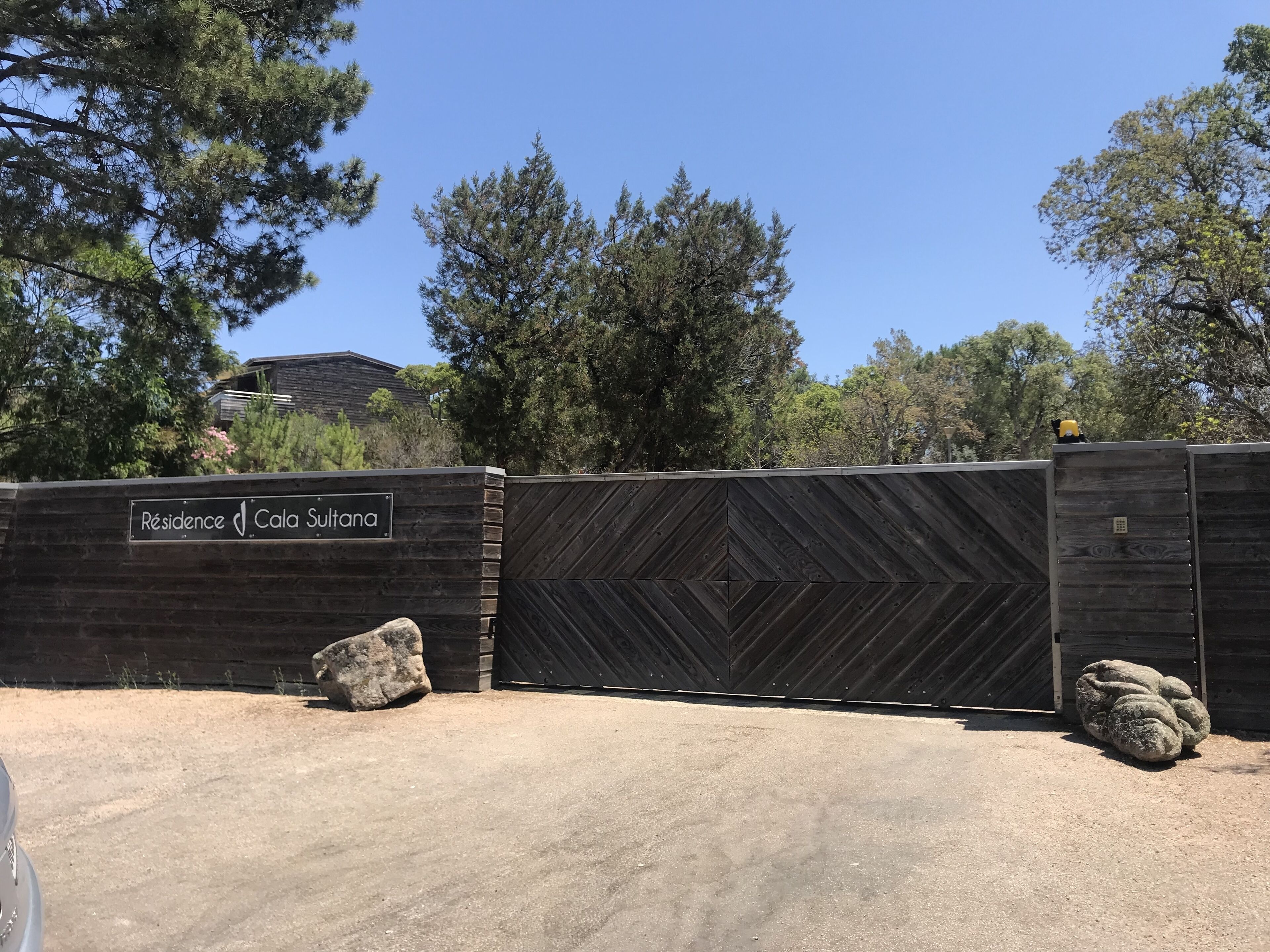 Una entrada cerrada con un cartel que dice 'Résidence Cala Sultana' y una valla de madera con un diseño geométrico.