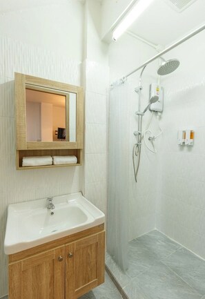 A modern bathroom with a wooden vanity, a mirror, and a shower area.