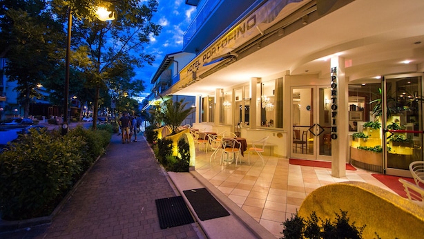 A hotel entrance with outdoor seating and a well-lit facade. - Casa Portofino Rooms&Breakfast (Cesenatico)