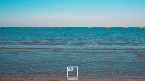 A beach with clear blue water, a rocky outcrop, and a distant lighthouse. - Casa Portofino Rooms&Breakfast (Cesenatico)