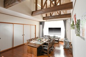Un área de comedor con una mesa y sillas de madera, un televisor y un divisor corredizo.