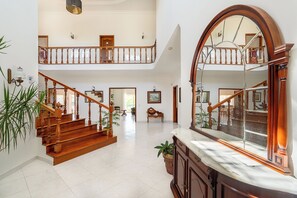 A spacious interior with a grand staircase, a large mirror, and a high ceiling.