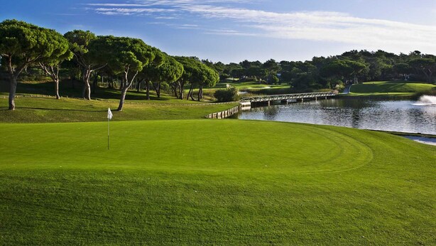 A golf course with a water hazard, trees, and a clear sky. - Villa Irene - Amazing Villa with private pool near beach and golf course (Almancil)
