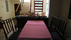 A staircase with a checkered tablecloth, potted plants, and a wooden railing. - Mabini Pensione (Puerto Princesa)