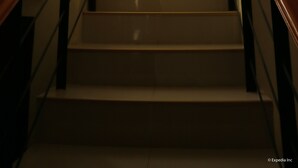 A staircase with wooden handrails, a wall with two framed floral paintings, and a view of greenery outside. - Mabini Pensione (Puerto Princesa)