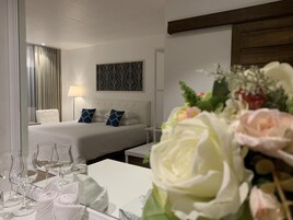 Habitación de hotel con cama, mesita de noche y un jarrón decorativo con flores.