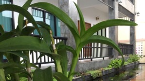 A modern building with a concrete facade, a wooden deck, and a small water feature with koi fish. - Phetcharat Grand Hotel Maesot (Mae Sot)