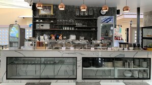 A modern cafe with a marble counter, copper pendant lights, and a variety of kitchenware and utensils. - Phetcharat Grand Hotel Maesot (Mae Sot)