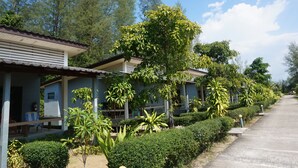 A row of single-story buildings with covered patios, surrounded by well-maintained greenery and trees. - Cousin Resort Koh Kho Khao Beach (Takua Pa)