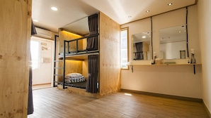 Una habitación con literas, paredes de madera, un espejo grande y suelo de madera.