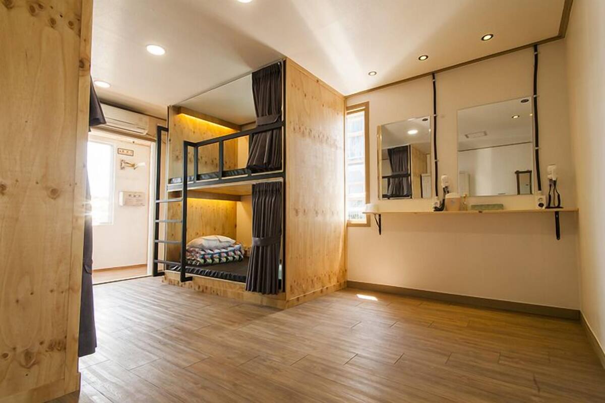 Une chambre avec un lit superposé, des murs en bois, un grand miroir et un plancher en bois.