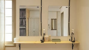 Un baño con espejo, toallero y estante con artículos de aseo.