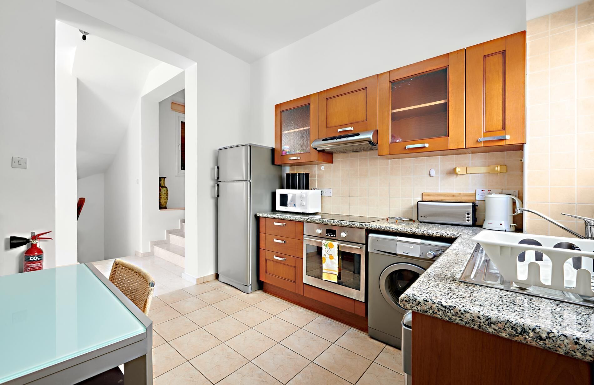 A compact kitchen with a refrigerator, microwave, toaster, oven, and washing machine.