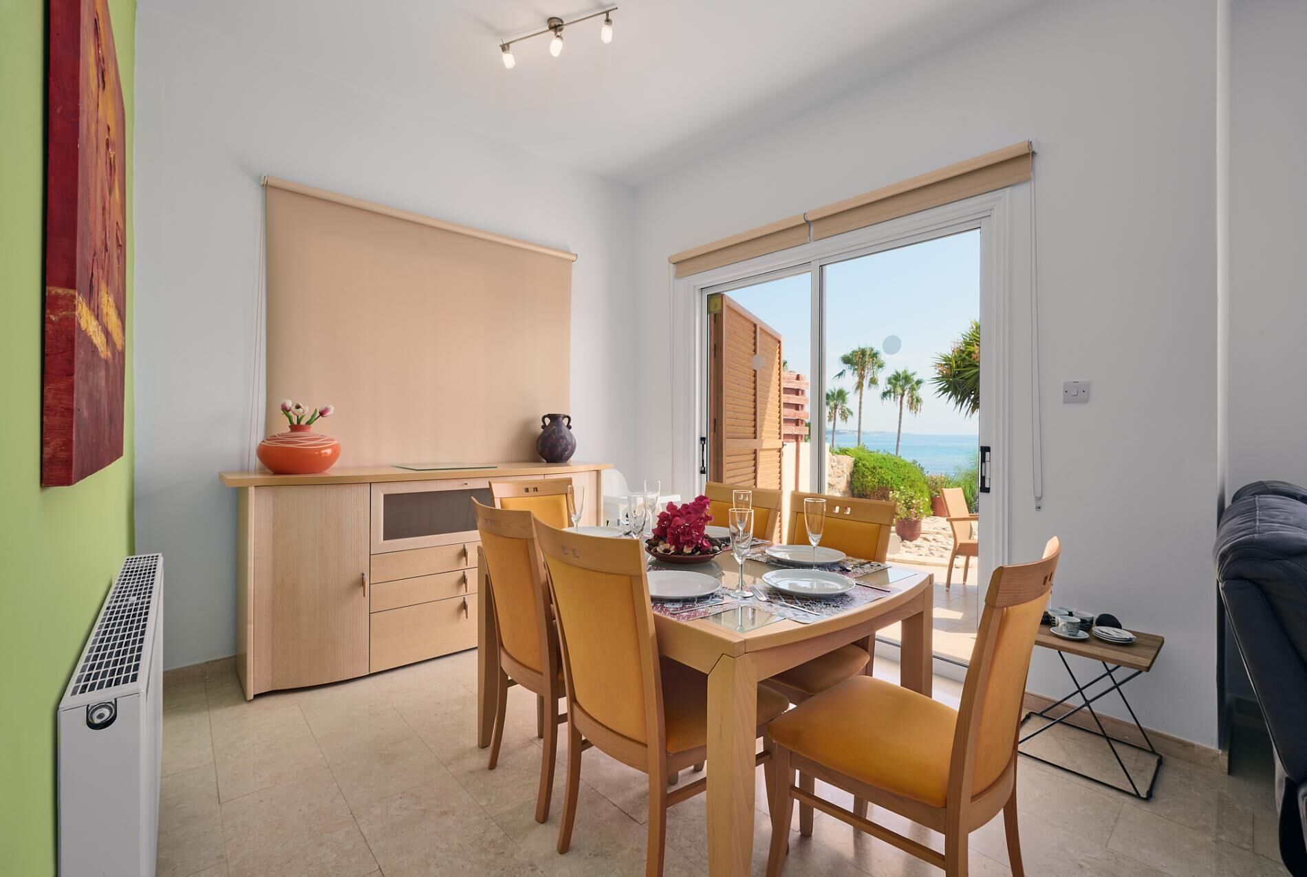 A dining area with a table set for four, a kitchen area, and a view of the beach.