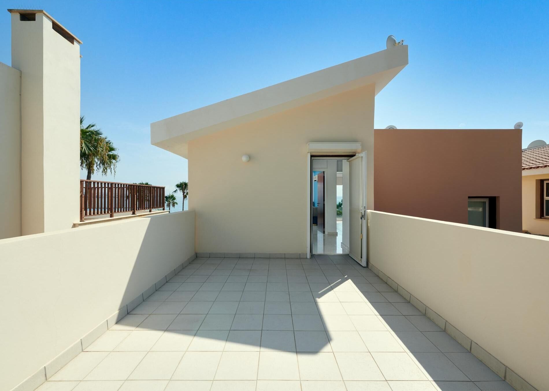 Un ampio balcone con pavimento piastrellato e una porta che dà su un ambiente interno.