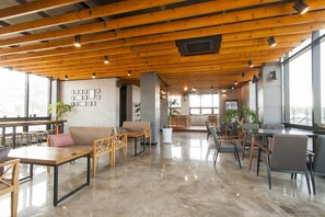Un vaste espace intérieur doté de poutres en bois, d’un mobilier confortable et de grandes fenêtres laissant entrer la lumière naturelle.