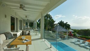 A modern outdoor lounge area with a pool, seating, and a glass railing overlooking a scenic view. - Family Luxury, Resort Level Amenities, Ocean Views, Perfect Location, Gym. (Jessups)