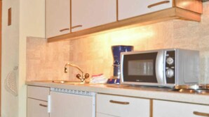 A kitchen with a dishwasher, a microwave, and a coffee maker on the counter.