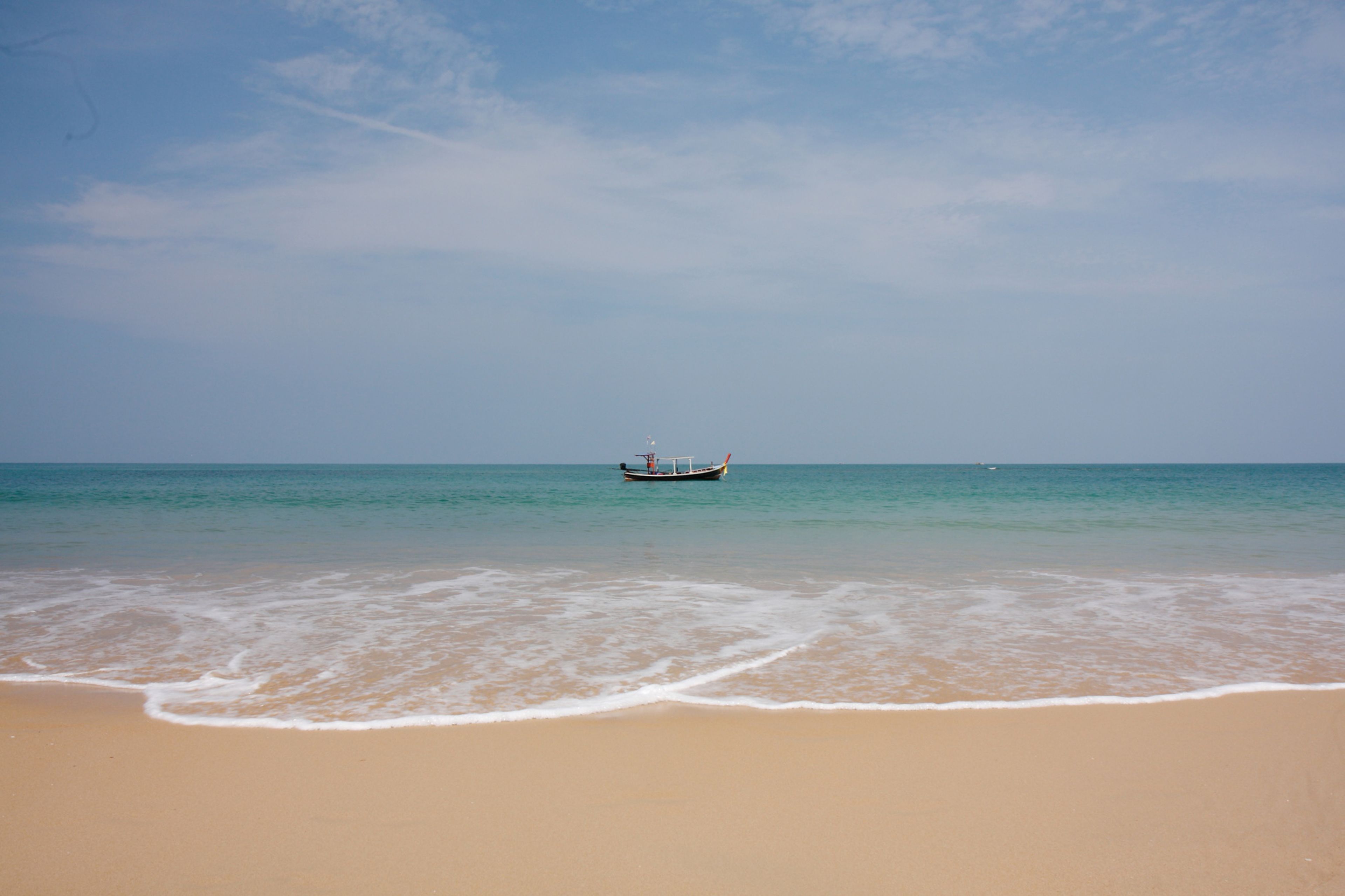Una playa con un bote en el agua y una orilla arenosa.