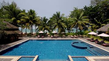 Relax by the oceanfront pool, surrounded by palm trees and lounge chairs.
