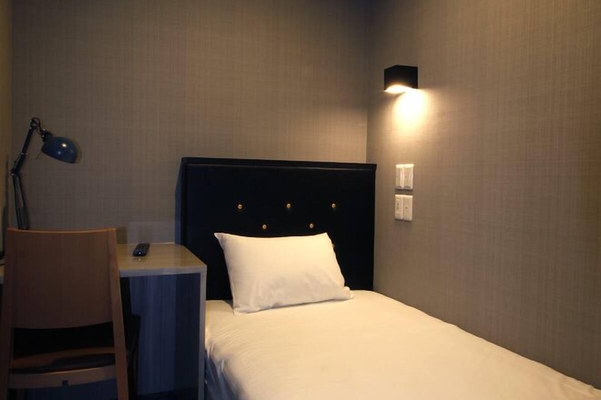 Una habitación de hotel con cama, escritorio, silla y lámpara.