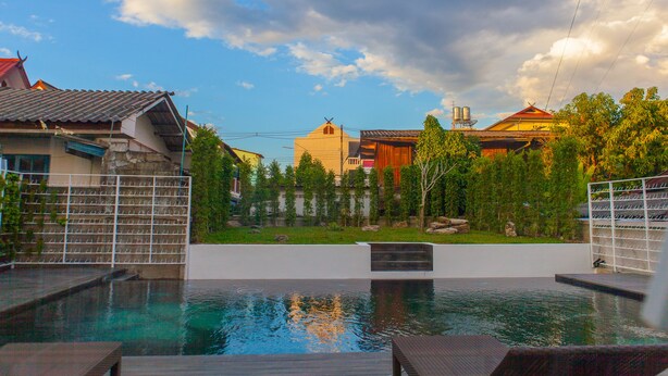 A swimming pool with a view of houses and a cloudy sky. - Meesuk Boutique House (Chiang Mai)